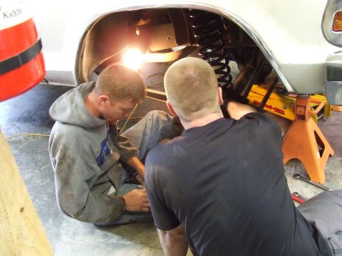 1979 Ford Bronco - Mechanics are seen working on the suspension system of a vehicle that is raised on jack stands.