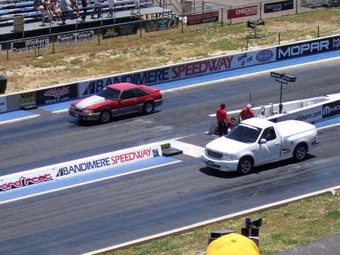 1972 Ford Ranchero - Two vehicles compete on the drag strip at Bandimere Speedway, with spectators in the background.