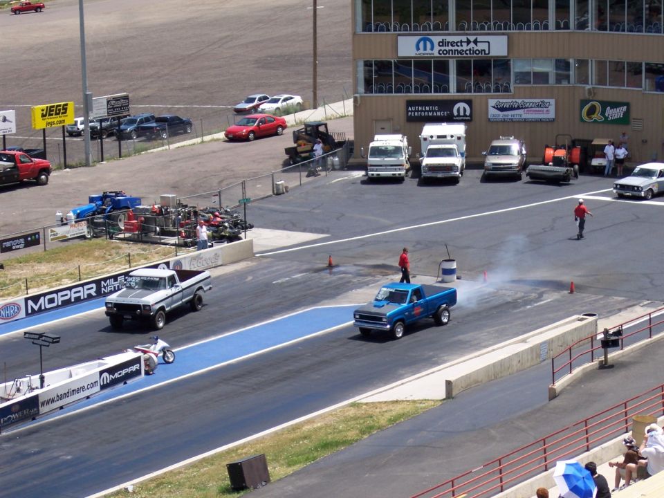 Blue pickup truck with smoke coming from exhaust on a drag strip