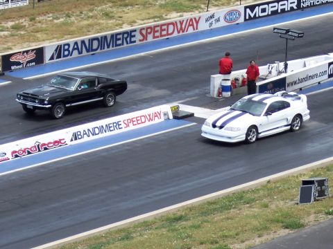 1972 Ford Ranchero - Two Ford Mustangs compete on the drag strip at Bandimere Speedway, with "Bandimere Speedway" signage visible.