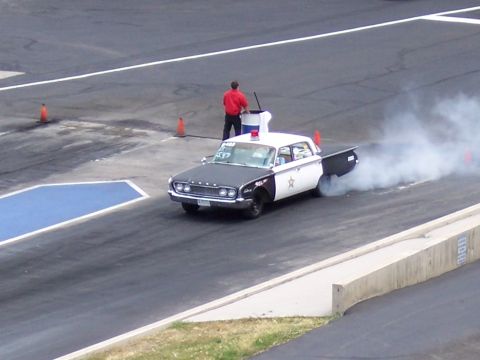 1972 Ford Ranchero - A vintage police car performs a burnout, creating a cloud of smoke on the drag strip.
