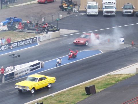 1972 Ford Ranchero - A yellow 1964 Ford Falcon Sprint races down the drag strip, kicking up smoke.