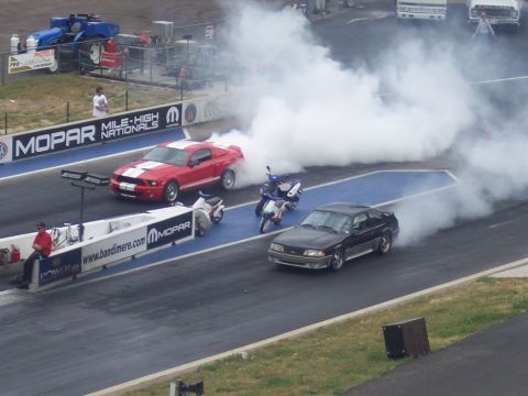 1972 Ford Ranchero - Two cars and two motorcycles are on a drag strip, with one car performing a burnout.