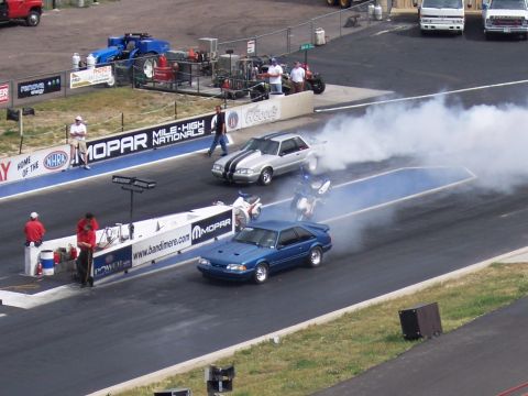 1972 Ford Ranchero - Cars and motorcycles compete in a drag race, with one vehicle generating a large cloud of smoke.