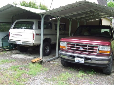 1979 Ford Bronco - Two Ford vehicles, a maroon Explorer and a white Bronco, are parked under a carport.