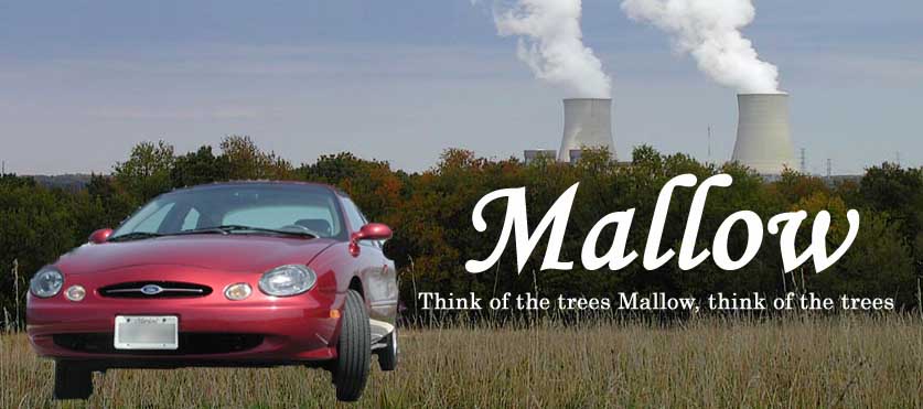 Red sedan parked in a field with two cooling towers emitting steam in the background