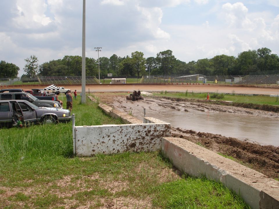 Mud bog with vehicles parked on the side and a vehicle in the mud