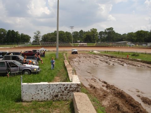 1989 Ford Bronco - Spectators and vehicles gather near a muddy track at a speedway event.