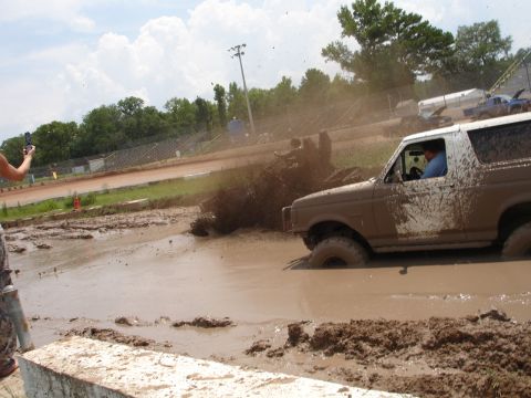 1989 Ford Bronco - A muddy Ford Bronco navigates a challenging mud bog at Putnam Speedway.