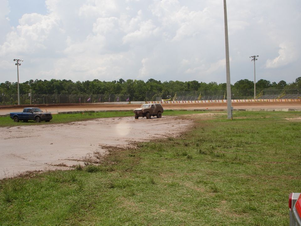Ford Bronco driving on a dirt track next to a pickup truck