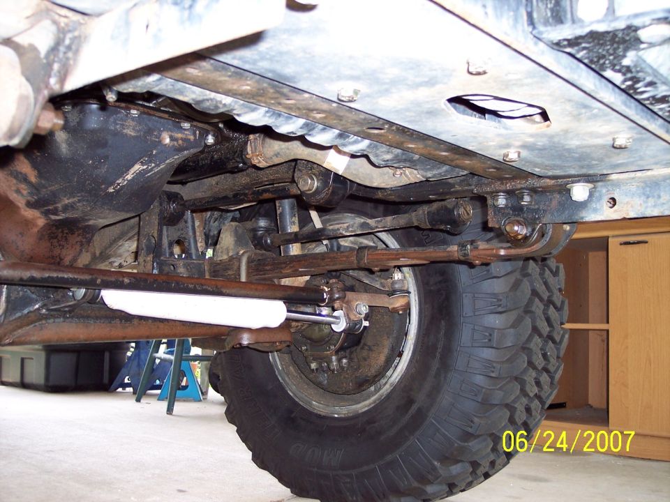Undercarriage view of a vehicle's front suspension and large tire