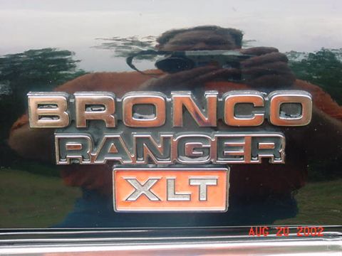 1979 Ford Bronco - Close-up of a Bronco Ranger XLT emblem on a dark vehicle's exterior.