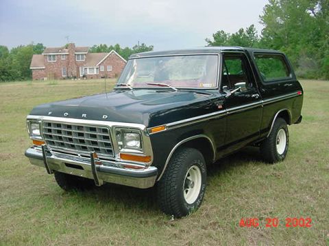 1979 Ford Bronco - This black 1979 Ford Bronco is parked on a grassy field with a house in the distance.