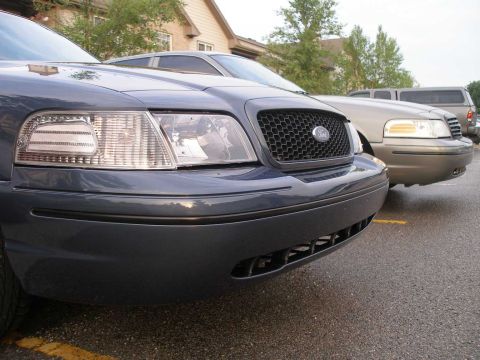 1998 Ford Crown Victoria - Two Ford Crown Victorias are parked side-by-side, with the front of the blue one prominently displayed.