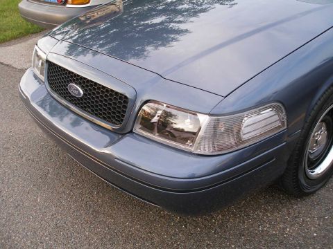 1998 Ford Crown Victoria - The front of a blue 1998 Ford Crown Victoria is shown, with a honeycomb grille and clear corner lamps.