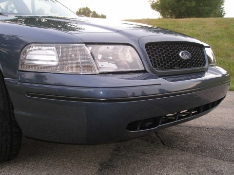 1998 Ford Crown Victoria - The front end of a blue Ford Crown Victoria is shown, a honeycomb grille and clear corner lamps.