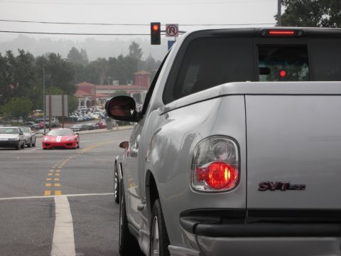 1998 Ford Crown Victoria - Silver SVT F150 pickup truck at intersection with red sports car ahead.