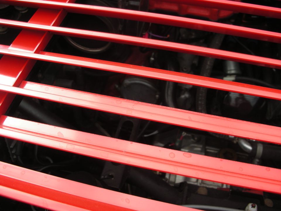 Close-up of a red grille with engine components visible behind it