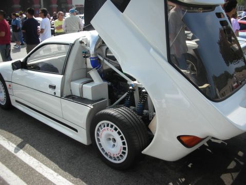 1998 Ford Crown Victoria - A white sports car is displayed with its engine and rear suspension exposed, OZ Racing wheels.