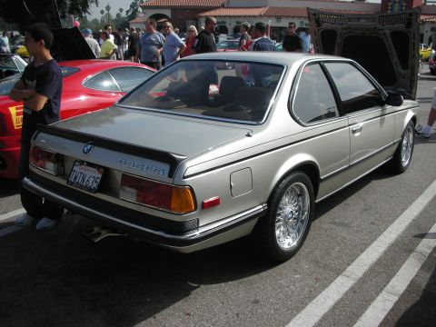 1998 Ford Crown Victoria - A silver BMW 635 CSi is parked at an outdoor car meet, with its hood open and other cars nearby.