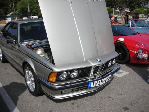 1998 Ford Crown Victoria - Silver BMW E24 coupe with hood open, parked next to a red Ferrari at a car meet.