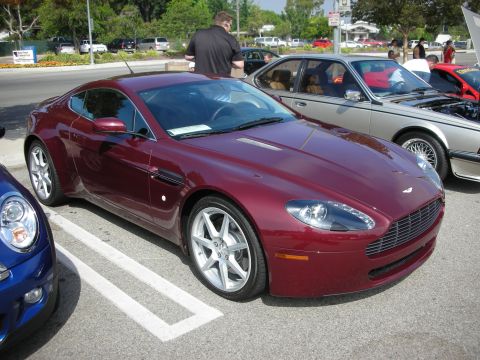 1998 Ford Crown Victoria - A maroon Aston Martin Vantage is parked in a lot with other vehicles, including a blue Mini Cooper and a silver BMW.