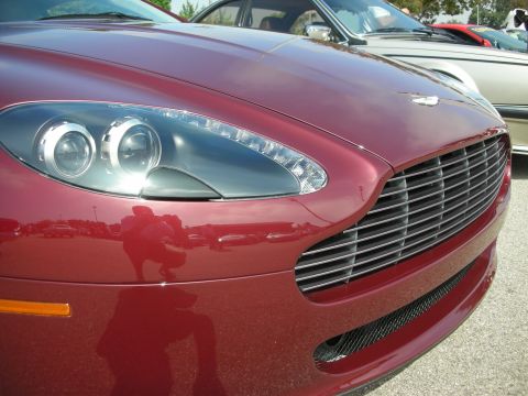 1998 Ford Crown Victoria - A red sports car is parked next to other vehicles, with its distinctive grille and headlights in focus.