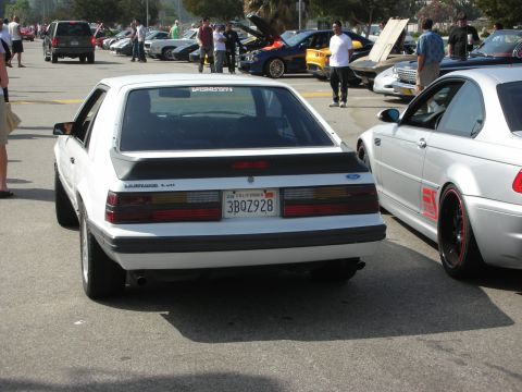 1998 Ford Crown Victoria - A white Ford Mustang LX 5.0 is parked next to a silver BMW at a car meet.