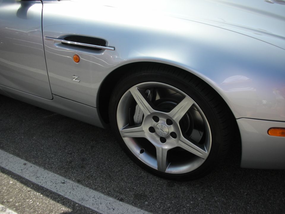 Silver sports car fender with side vent and five-spoke wheel
