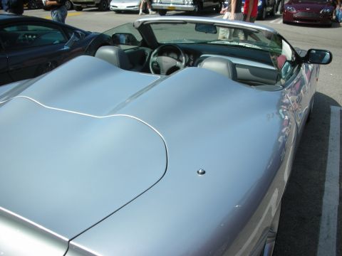 1998 Ford Crown Victoria - A silver convertible sports car is parked in a lot with other vehicles visible in the background.