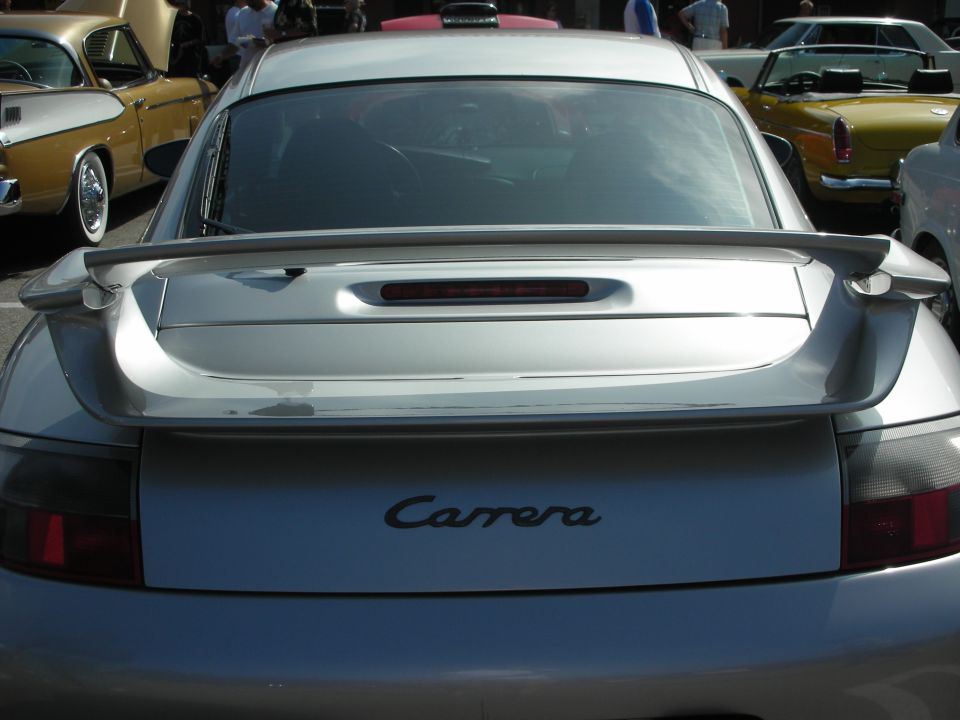 Silver Porsche 911 Carrera with a large rear spoiler. Other cars visible in background