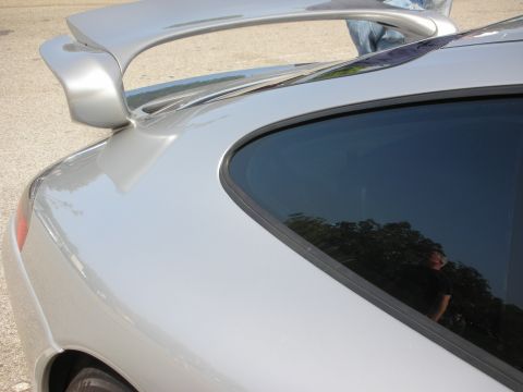 1998 Ford Crown Victoria - A close-up view of the rear spoiler and window of a silver Porsche 911.