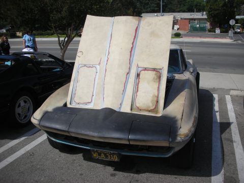 1998 Ford Crown Victoria - A car with its hood open, revealing an unfinished interior and front end, parked next to another vehicle.