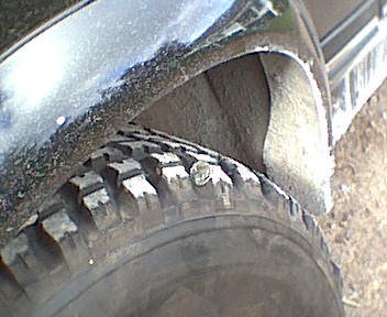 1989 Ford Bronco - A close-up view of a vehicle's tire and the surrounding wheel well, showing some dirt and wear.