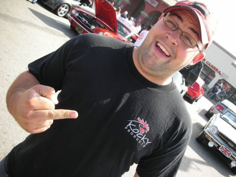 1998 Ford Crown Victoria - A man gestures with his middle finger in front of a gathering of cars.