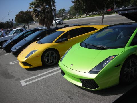 1998 Ford Crown Victoria - A line of exotic cars, including a bright green Lamborghini Gallardo, are parked in a lot.