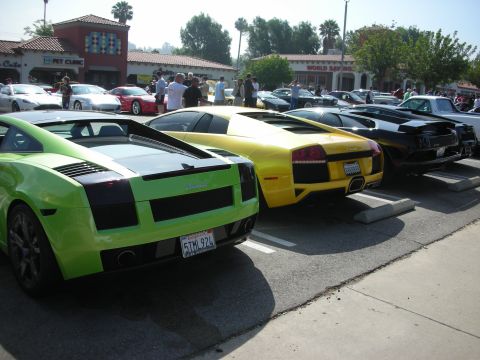 1998 Ford Crown Victoria - Multiple exotic sports cars, including Lamborghinis, are parked in a lot on a sunny day.