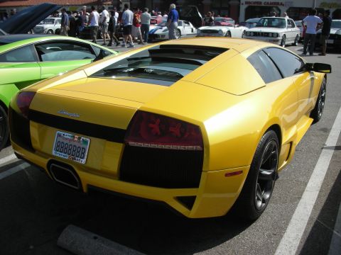 1998 Ford Crown Victoria - A yellow Lamborghini is parked at an event with other vehicles and people in the background.