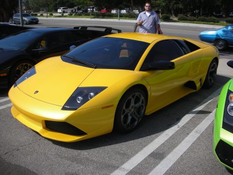 1998 Ford Crown Victoria - Three exotic sports cars, including a yellow Lamborghini, are parked in a lot.