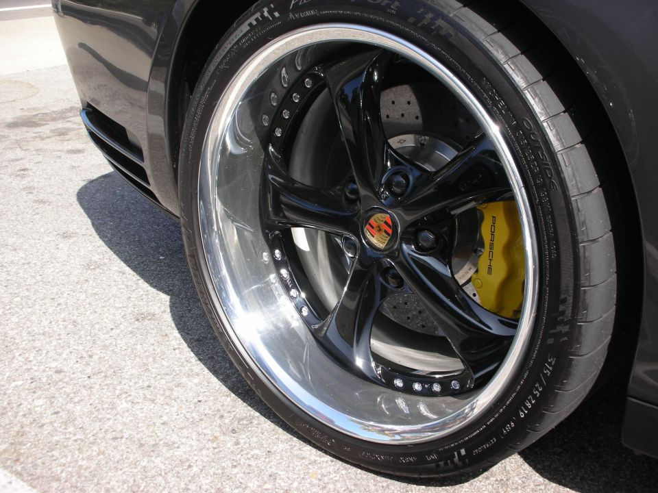 Black car wheel with yellow Porsche brake caliper and custom chrome rim