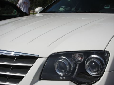 1998 Ford Crown Victoria - A close-up view of the front of a white Chrysler Crossfire, with a person standing near the driver's side door.