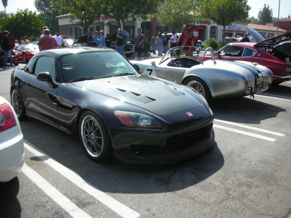 Black Honda S2000 parked next to a silver AC Cobra and a red Datsun Z car
