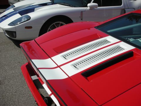 1998 Ford Crown Victoria - Two sports cars, one red and one white with blue stripes, are parked side-by-side.