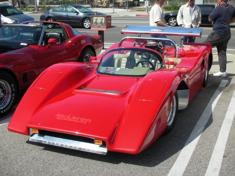 1998 Ford Crown Victoria - A bright red McLaren race car is parked at a car meet, with other vehicles visible in the background.