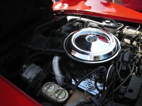 1998 Ford Crown Victoria - The engine bay of a red car is shown, a prominent chrome air filter housing and various engine components.