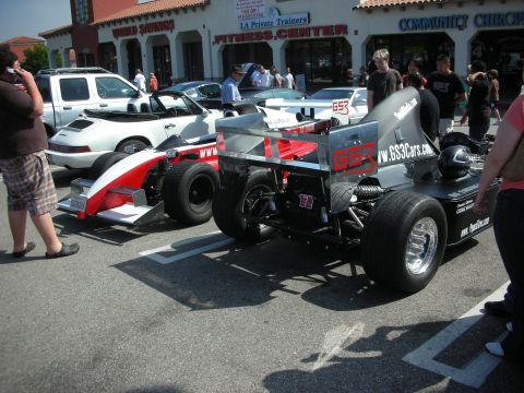 1998 Ford Crown Victoria - Two open-wheel race cars are parked in a lot, one with prominent "GS3Cars.com" branding.