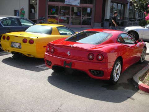 1998 Ford Crown Victoria - Two sports cars, a red Ferrari and a yellow Corvette, are parked in a lot.