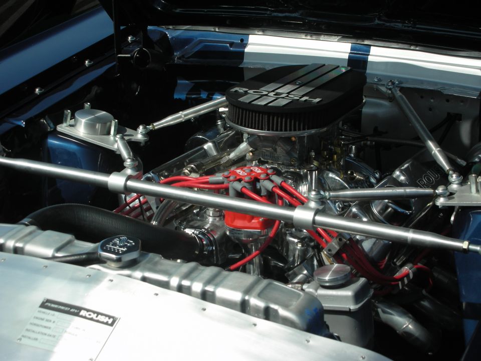 Close-up of a shiny engine bay with a ROUSH air filter and red spark plug wires