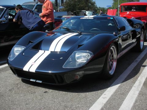 1998 Ford Crown Victoria - A dark blue Ford GT with white racing stripes is parked at a car meet.