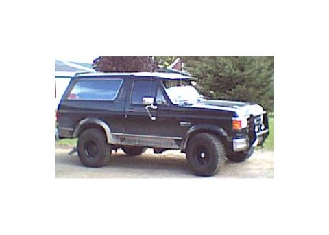 1989 Ford Bronco - A black Ford Bronco SUV is shown from a 3/4 front angle, equipped with a bull bar and roof rack.